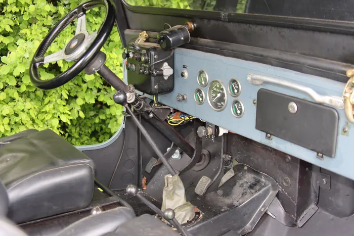 Innenraum eines hellblauen Oldtimer-Jeeps mit Lenkrad, Armaturenbrett und Schalthebel.