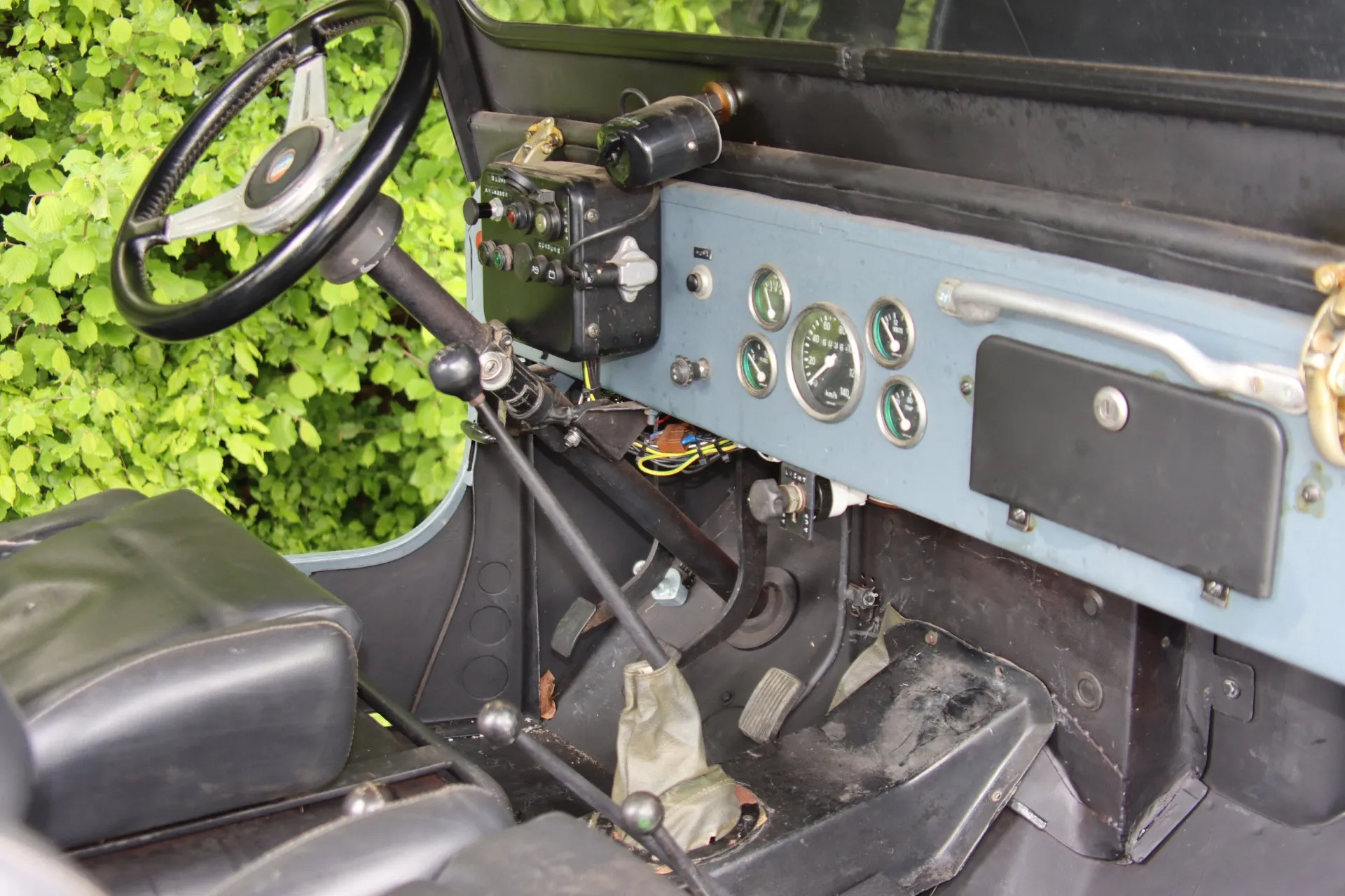 Innenraum eines hellblauen Oldtimer-Jeeps mit Lenkrad, Armaturenbrett und Schalthebel.