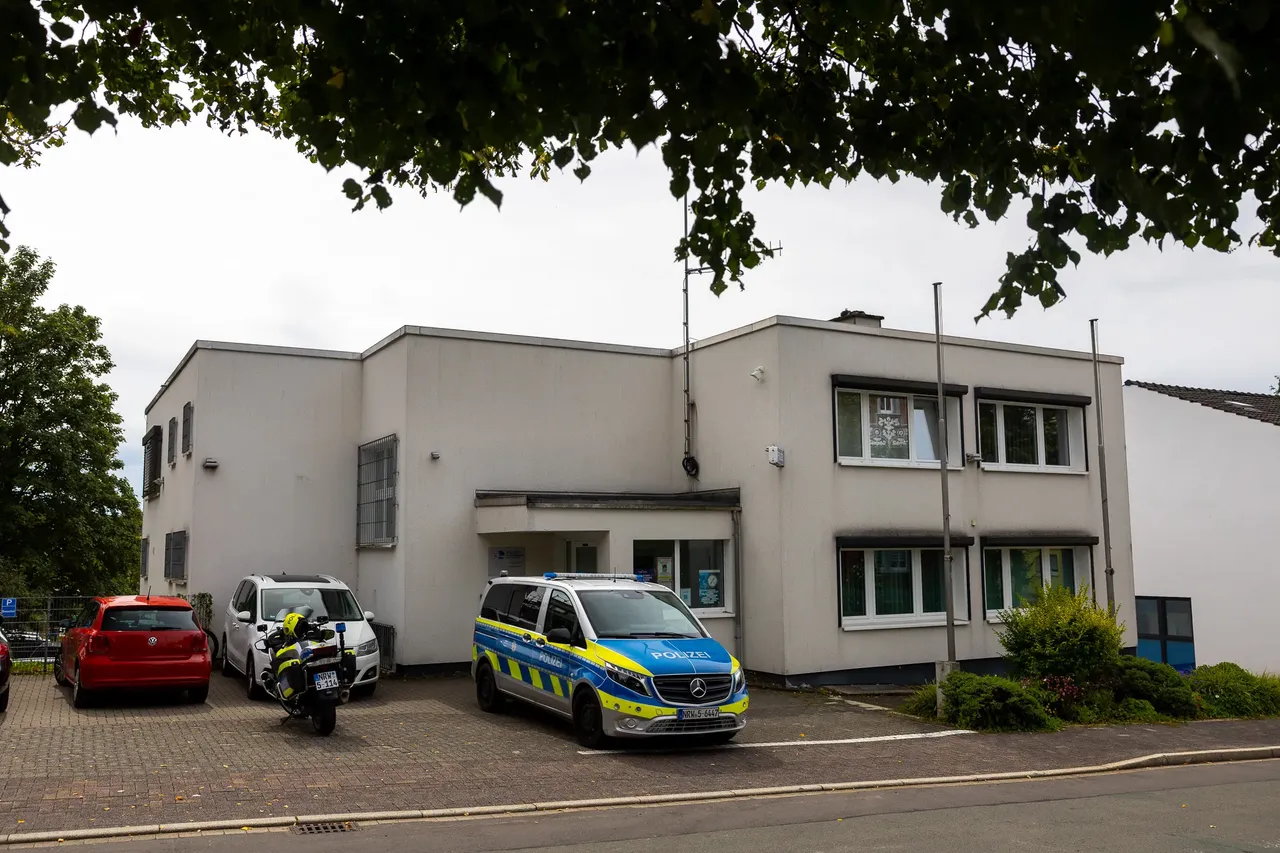 Ein blau-gelber Polizeiwagen und ein Motorrad parken vor einem weißen, zweistöckigen Gebäude.