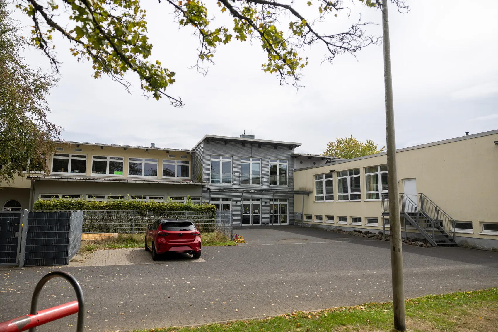 Modernes Schulgebäude der Regenbogenschule Halver mit einem roten Auto auf dem Vorplatz.