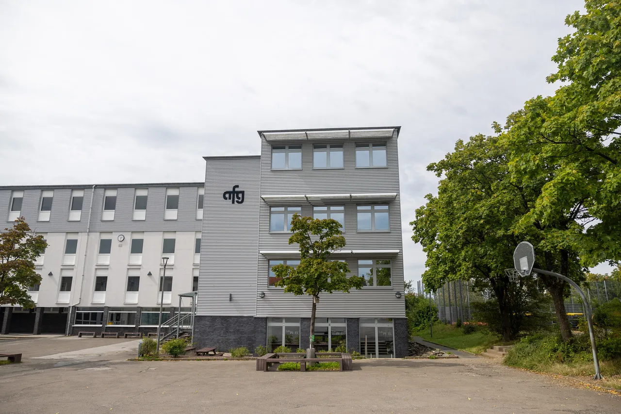 Modernes Schulgebäude des Anne-Frank-Gymnasiums Halver mit grauer Fassade, dem Logo „afg“ und einem gepflasterten Vorplatz.