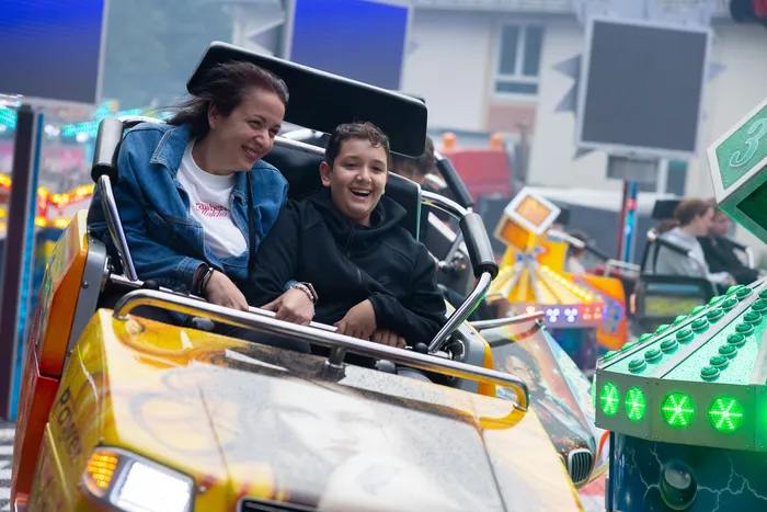Eine Frau und ein Junge lachen während einer Fahrt auf einem Karussell auf der Kirmes.