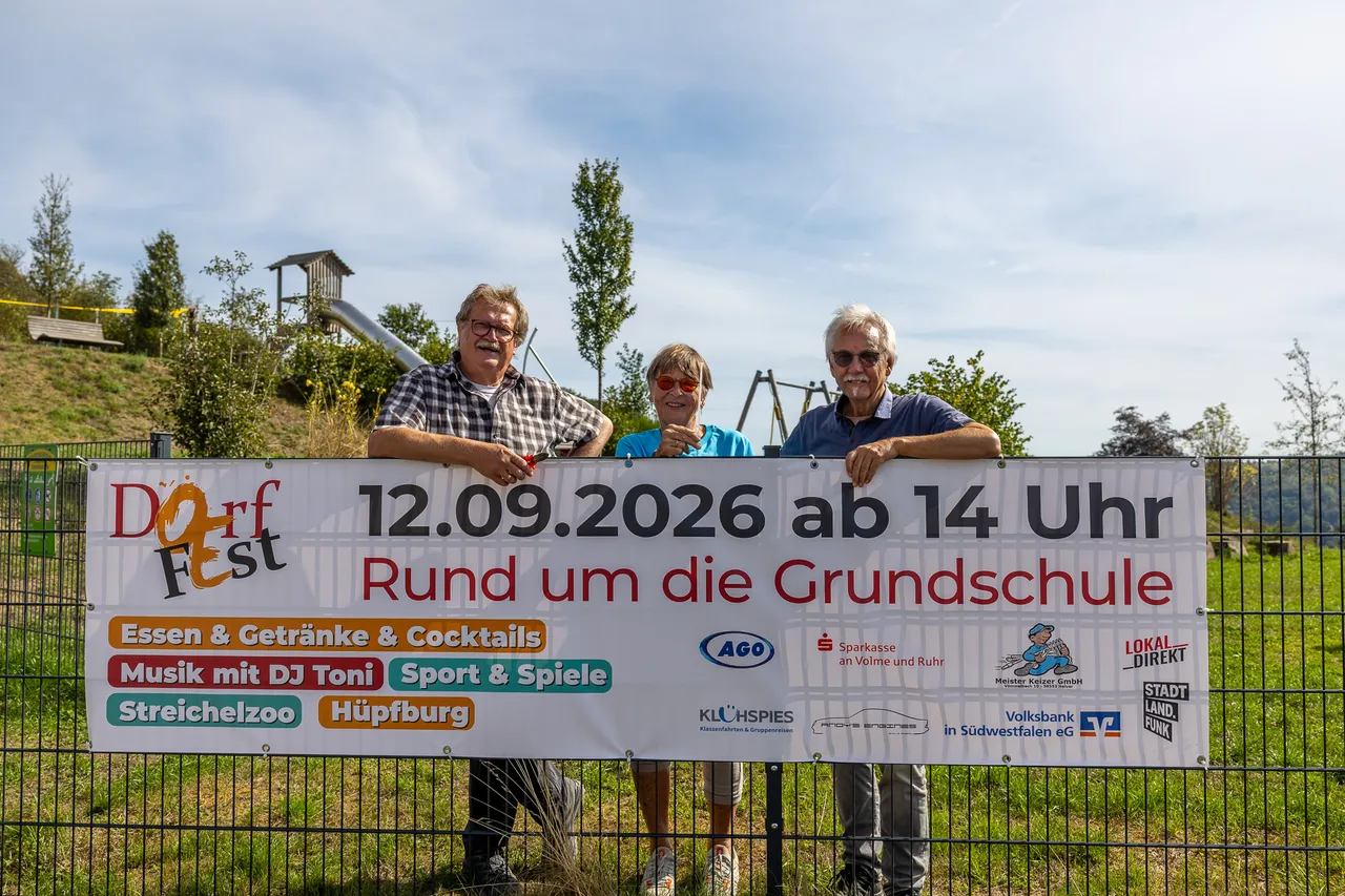 Drei Personen halten ein Banner für das Dorffest in Oberbrügge am 12. September 2026.