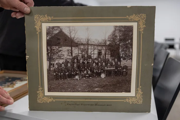 Eine Schwarzweißaufnahme aus dem Jahr 1910 zeigt die Freiwillige Feuerwehr Bommert vor einem Gebäude. Die Gruppe besteht aus etwa 30 Männern in Uniformen. Darunter steht der Text 