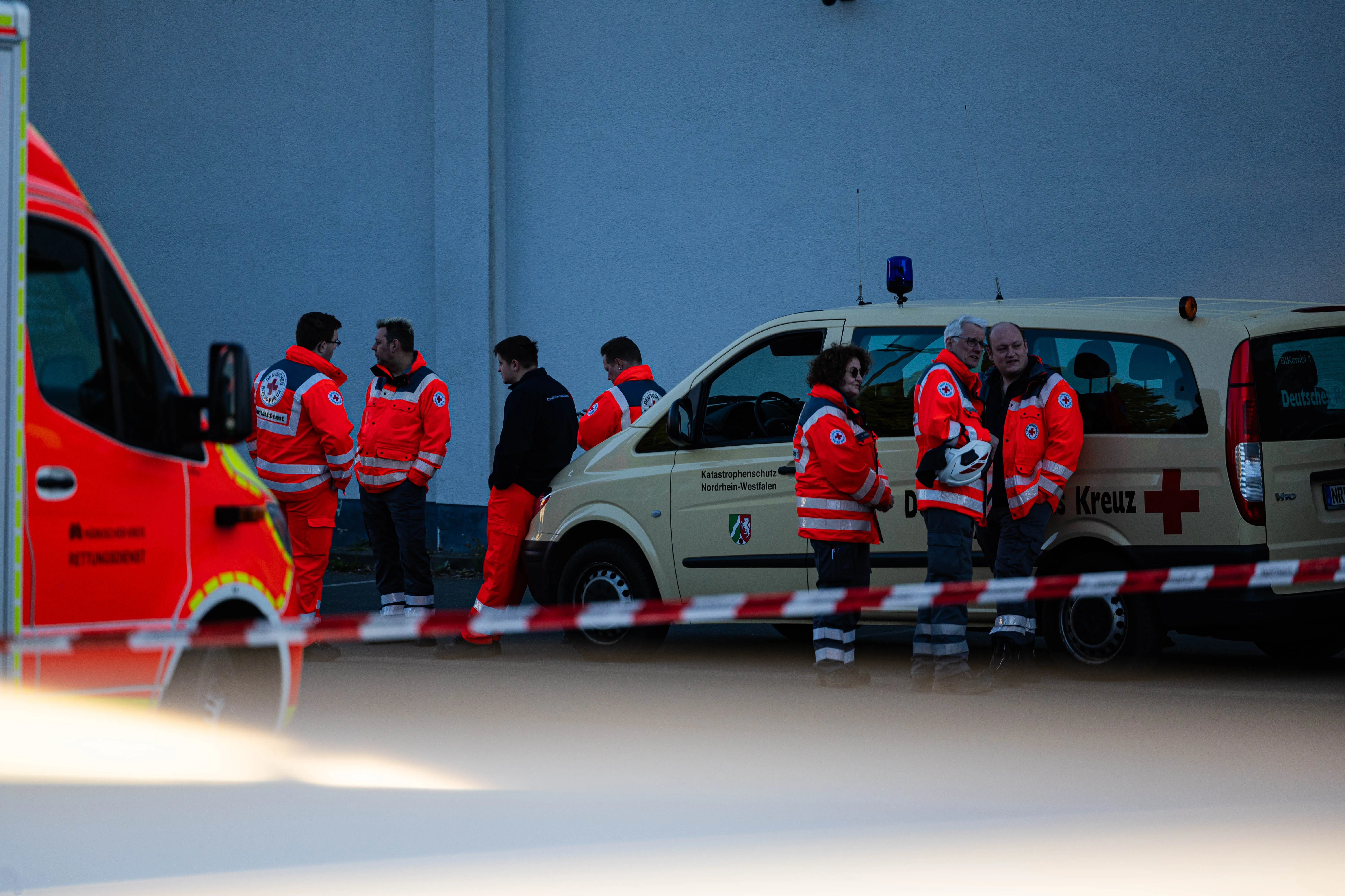 Rettungskräfte des Deutschen Roten Kreuzes und ein Rettungswagen vor einem Gebäude nach einem Brand in Kierspe.