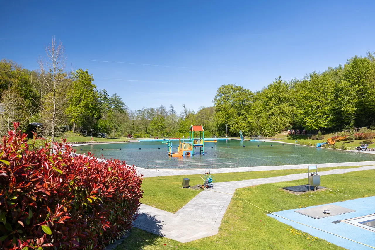 Freizeitbad Herpine mit Wasserfläche, Sprungturm und Liegewiese im Grünen, vorbereitet für die Eröffnung.