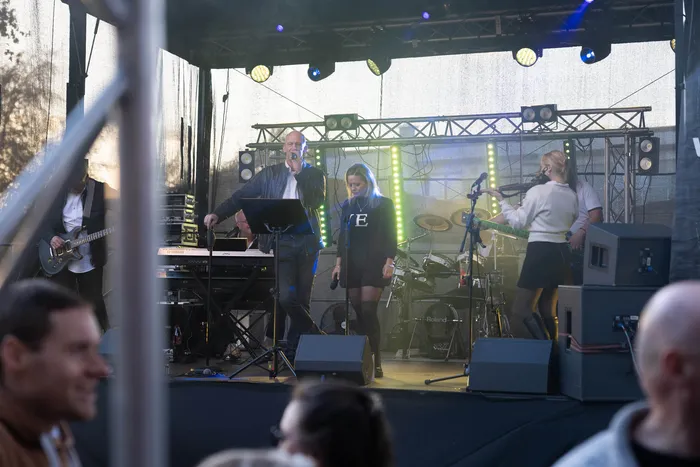 Eine Band tritt auf einer beleuchteten Bühne bei einem Gemeindefest auf.