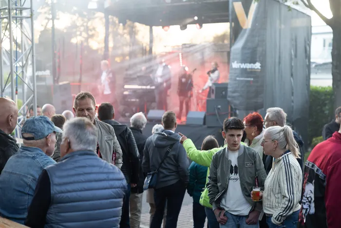 Menschen beobachten eine Live-Musik-Performance auf einer beleuchteten Bühne bei einem Gemeindefest.