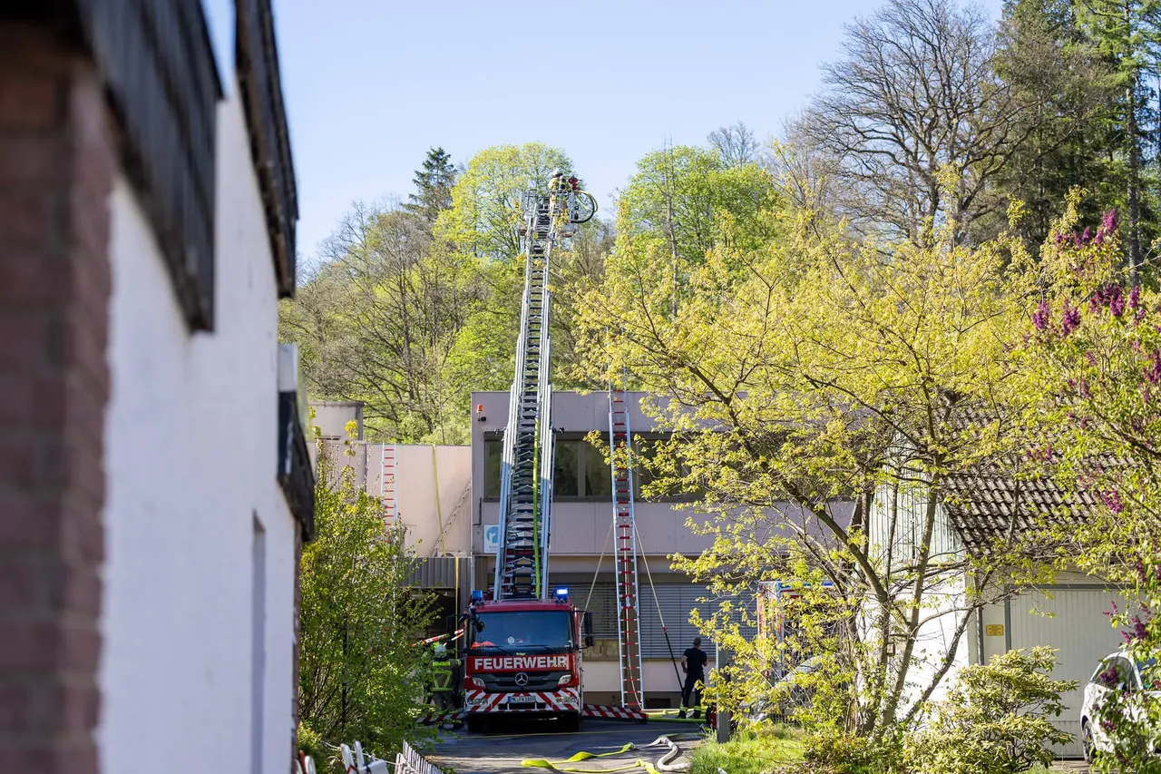 Feuerwehrwagen mit ausgefahrener Leiter vor einem mehrstöckigen Gebäude, Einsatzkräfte sind auf der Leiter zu sehen.