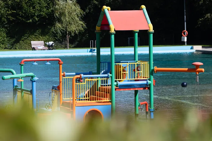 Ein buntes Wasserspielgerät mit rotem Dach und gelben Geländern steht in einem Schwimmbecken im Waldfreibad Herpine.