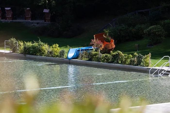 Blaue Wasserrutsche am Rand eines Schwimmbeckens im Waldfreibad Herpine.