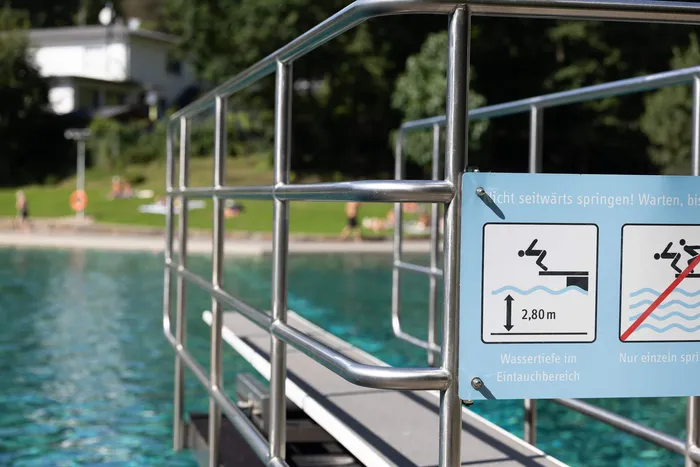 Metallgeländer eines Sprungbretts am Pool mit einem Hinweisschild zur Wassertiefe von 2,80 Metern.