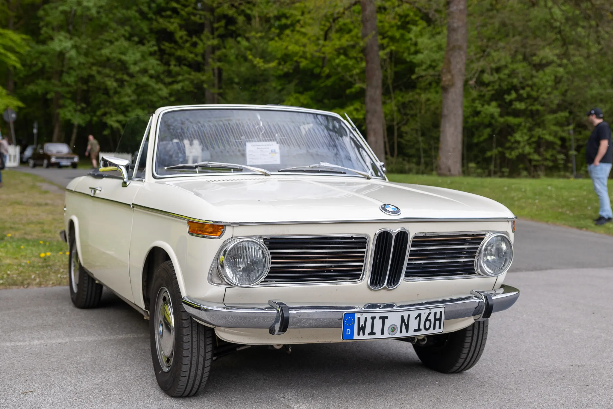 Cremefarbener BMW 1600 Cabriolet aus den 1960er Jahren steht auf einem Parkplatz, Kennzeichen WIT-N 16H.