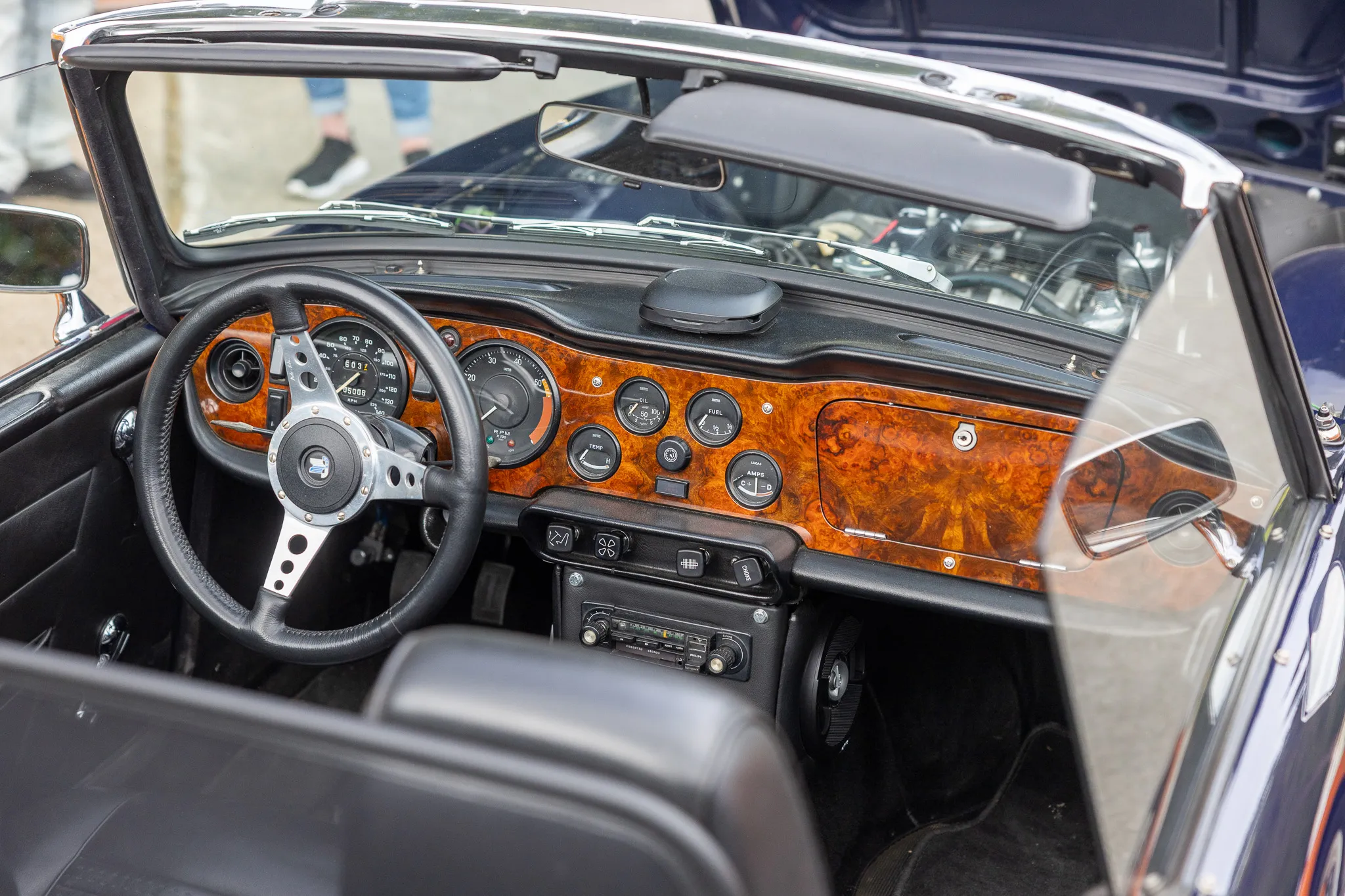 Detailaufnahme des Armaturenbretts eines klassischen Oldtimers mit Holzverkleidung, Lenkrad und zahlreichen Instrumenten.