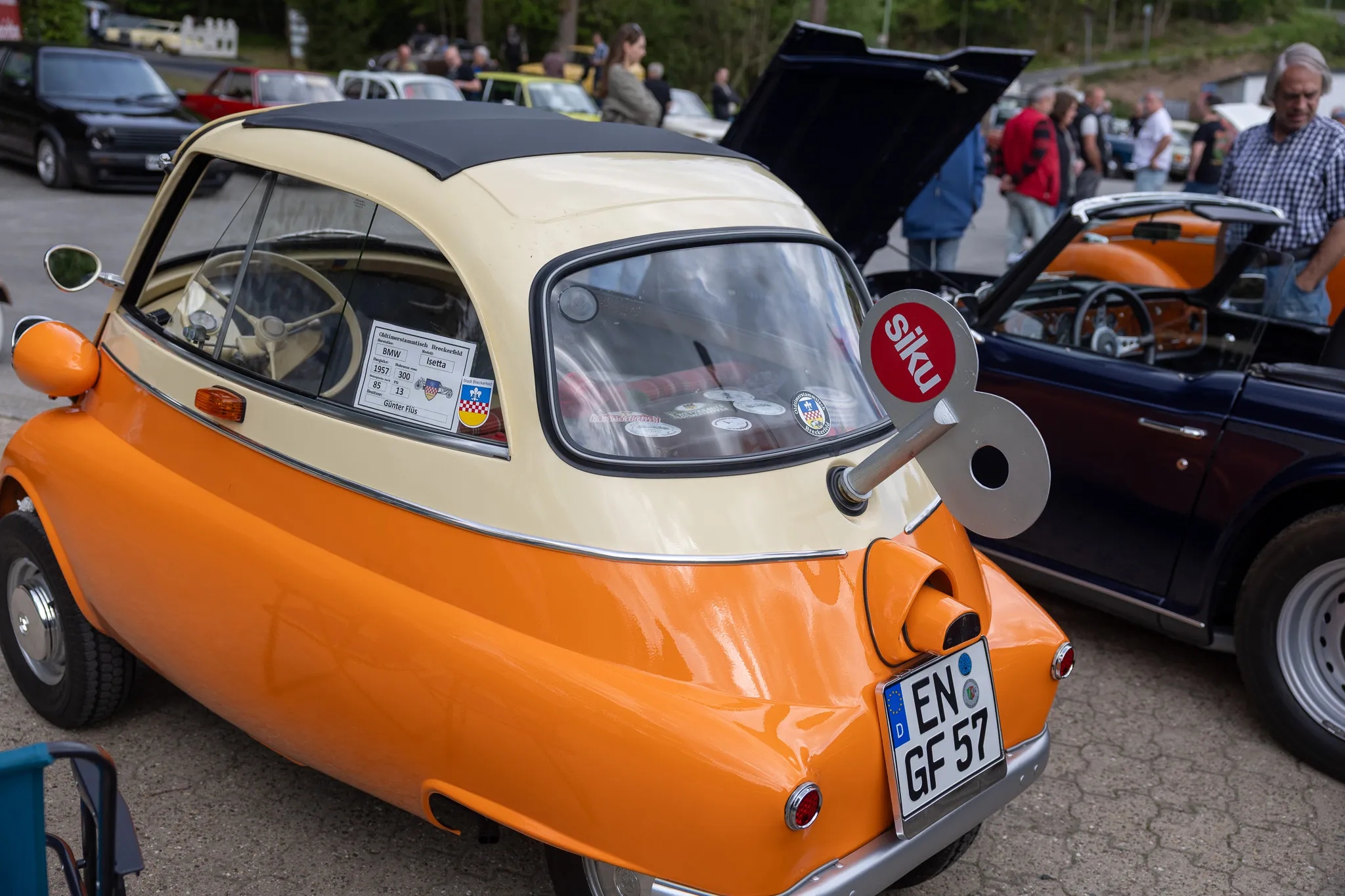 Heckansicht eines orange-beigen BMW Isetta mit Siku-Werbeaufkleber und Kennzeichen EN-GF 57 auf einem Oldtimertreffen.