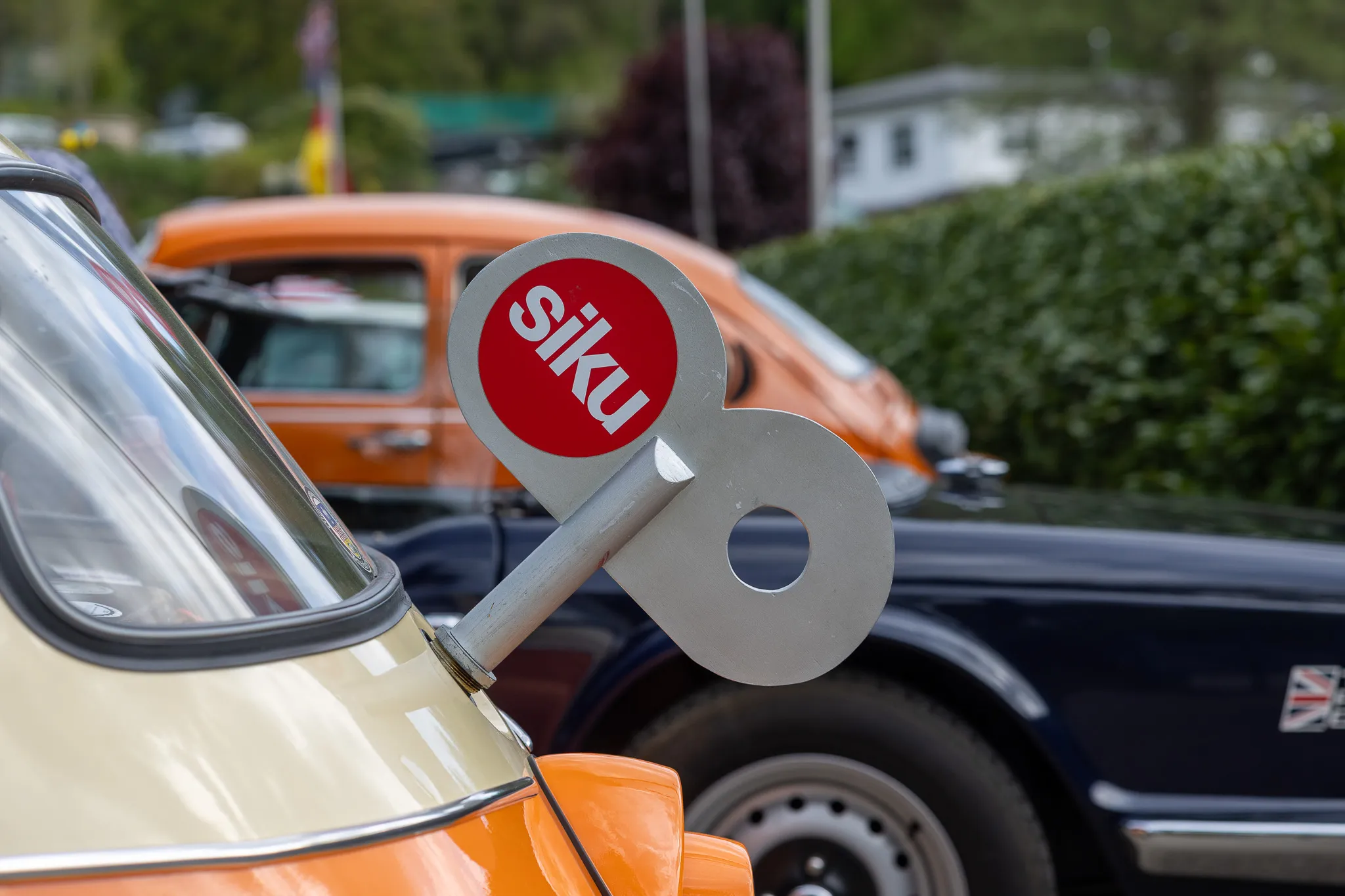 Ein Oldtimer mit einem silbernen Schlüsselanhänger mit rotem Siku-Logo auf der Motorhaube.