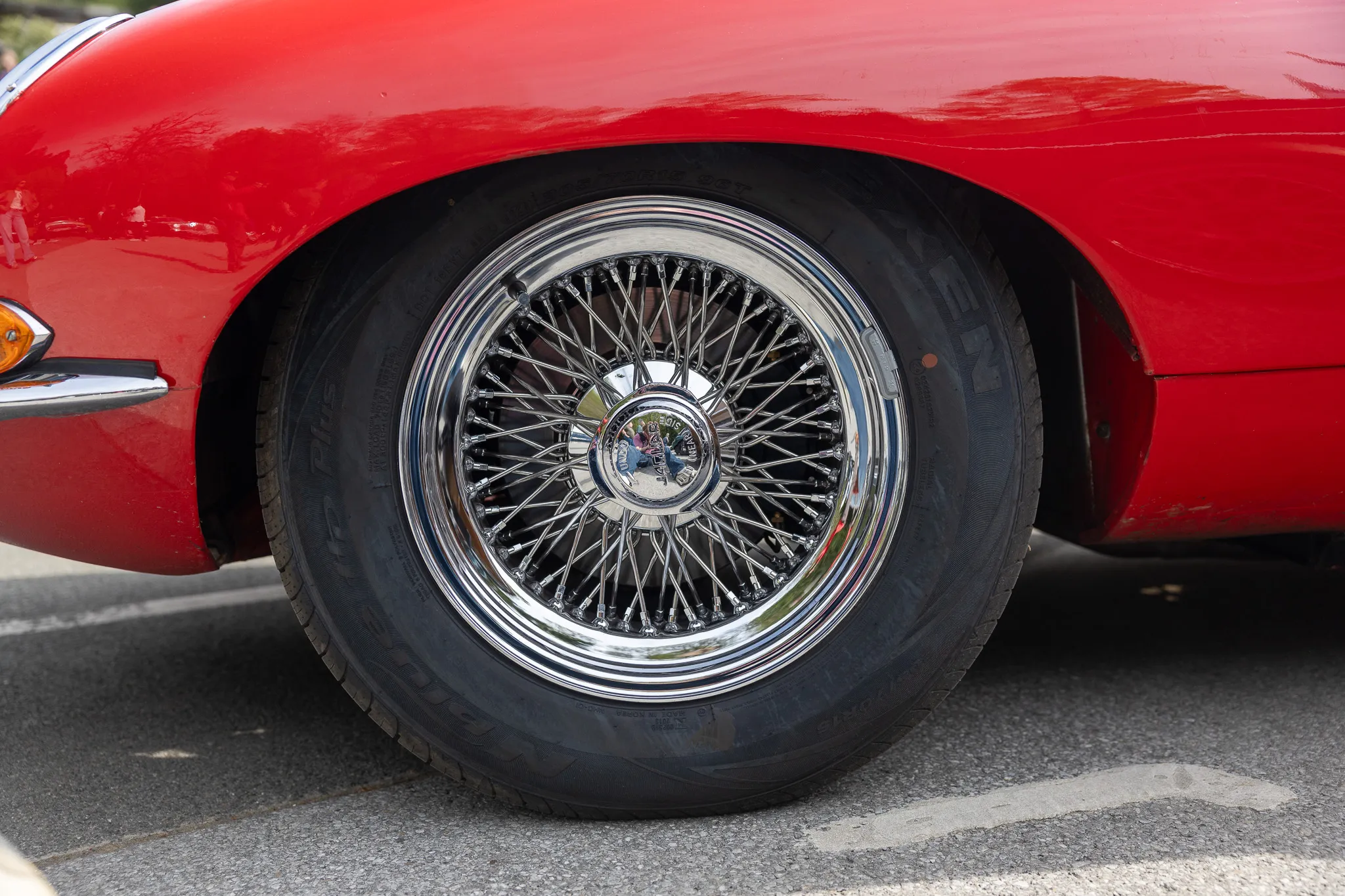 Detailaufnahme eines Speichenrads mit Reifen an einem roten Oldtimer.
