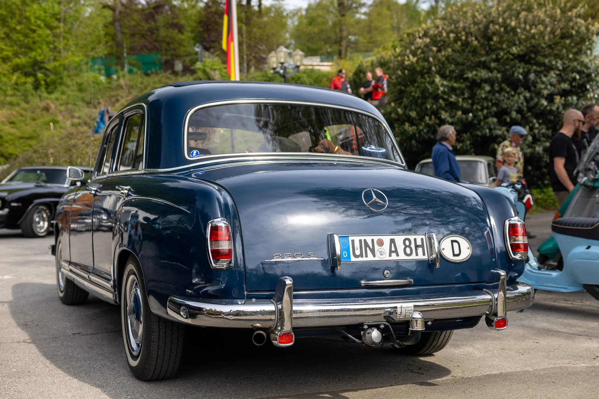 Heckansicht eines dunkelblauen Mercedes-Benz 220S Oldtimers mit deutschem Kennzeichen bei einem Oldtimertreffen.