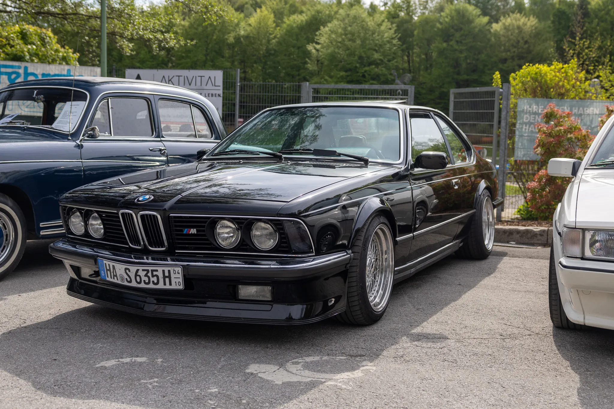 Schwarzer BMW Oldtimer mit Kennzeichen HA-S 635 H steht auf einem Parkplatz vor Büschen und einem Zaun.