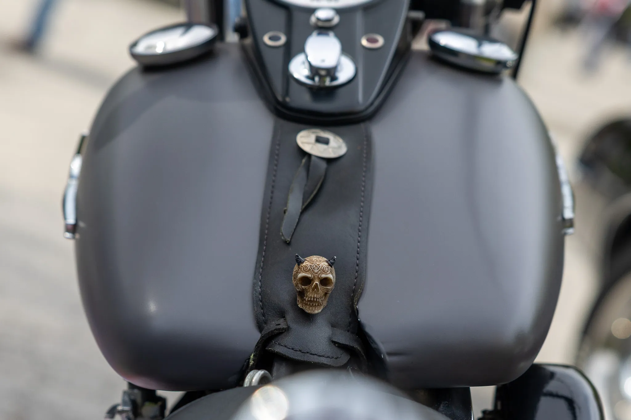 Schwarzer Motorradtank mit Totenkopf-Emblem und Lederbezug.