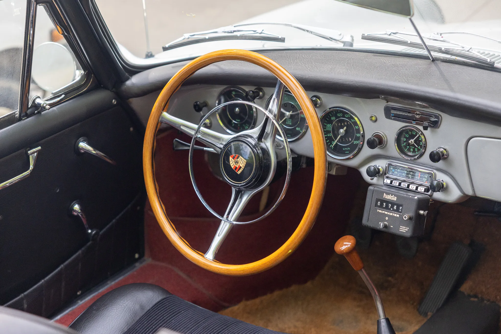 Innenraum eines klassischen Autos mit Holzlenkrad, Instrumententafel und einem Halda-Tripmaster.