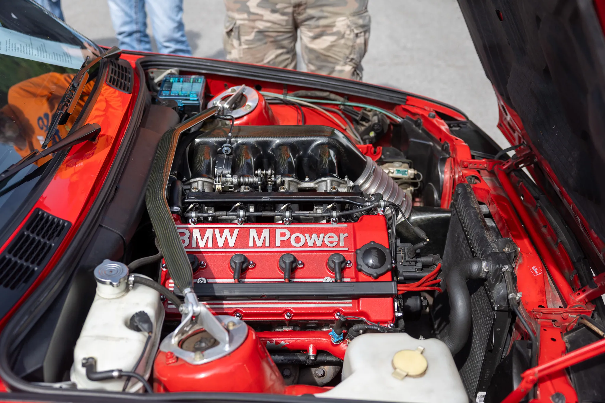Motorraum eines roten Oldtimers mit dem Aufdruck „BMW M Power“.