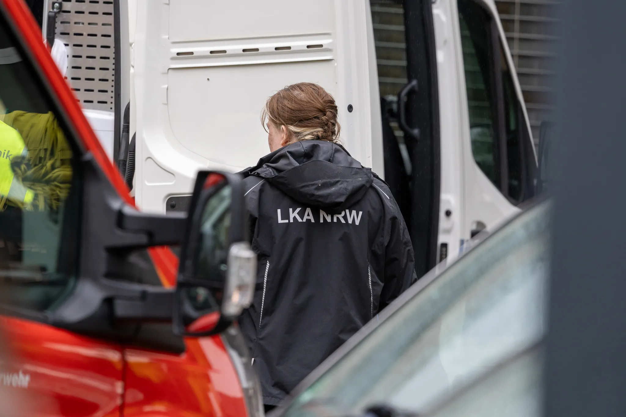Eine Ermittlerin des Landeskriminalamts Nordrhein-Westfalen (LKA NRW) geht an einem Transporter vorbei, während im Hintergrund ein weiteres Fahrzeug steht.