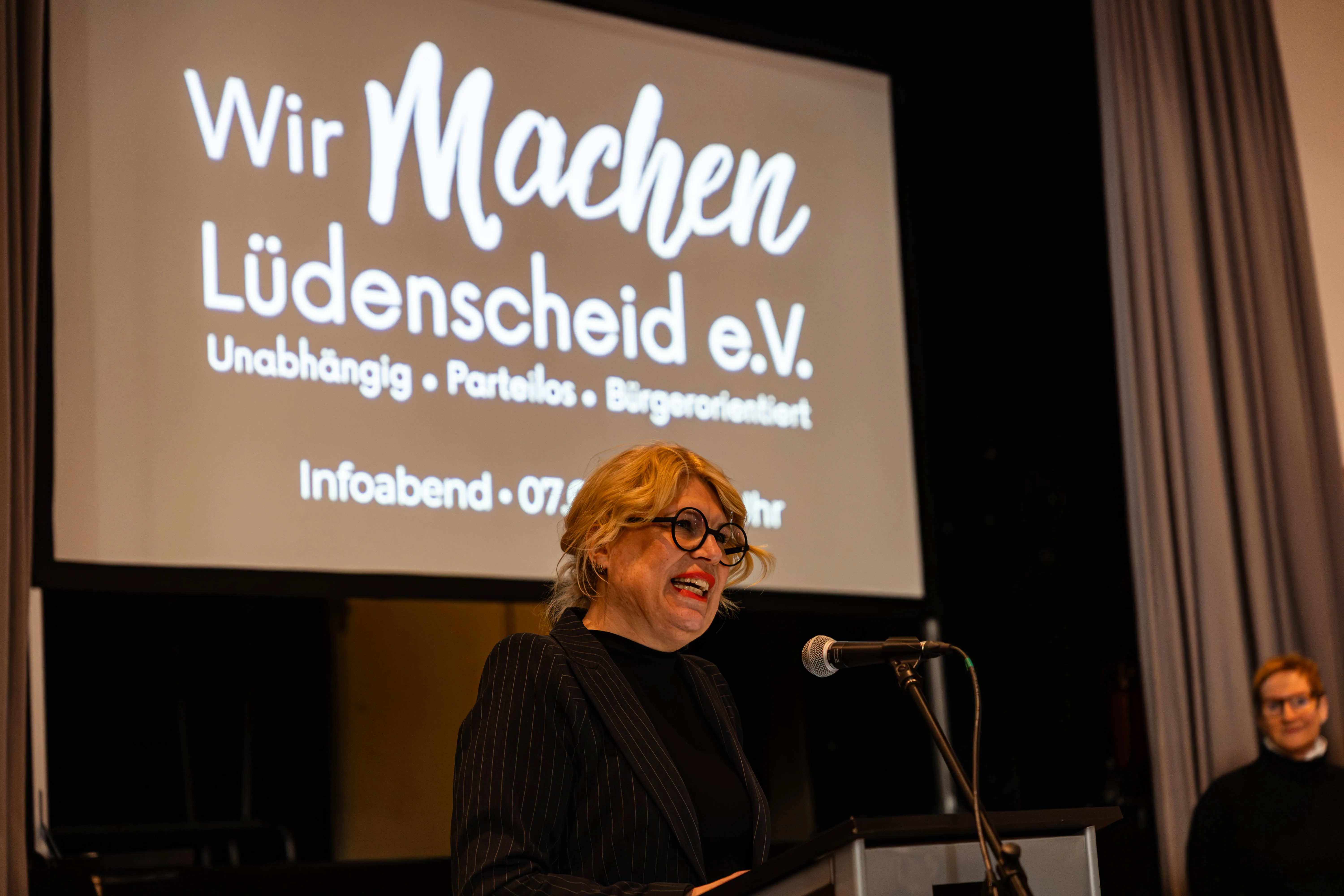 Zdenka Schwabbauer spricht an einem Rednerpult vor einer Leinwand mit dem Schriftzug „Wir Machen Lüdenscheid e.V.“