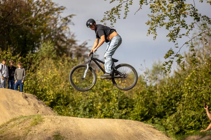 Ein Mann springt mit einem BMX-Rad über Erdhügel im Bikepark Halver.