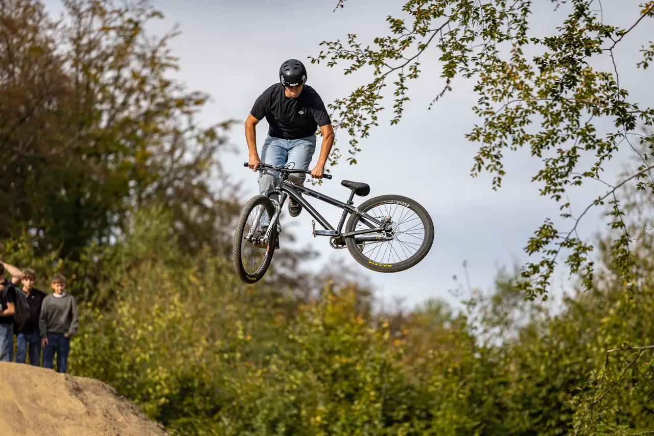 Ein Mann mit Helm springt mit einem BMX-Rad hoch in der Luft.