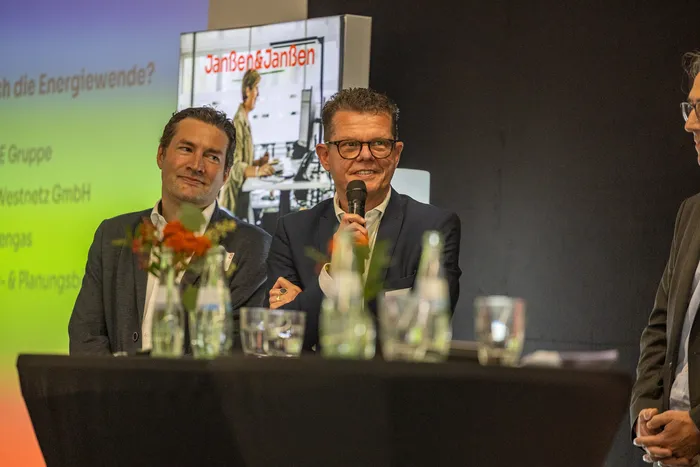 Ein Mann spricht in ein Mikrofon während einer Podiumsdiskussion bei der Jubiläumsfeier von Janßen & Janßen.