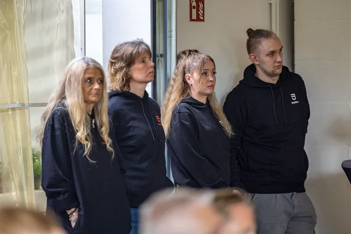 Vier Personen in schwarzen Kapuzenpullovern stehen nebeneinander bei der Jubiläumsfeier von Janßen&Janßen.