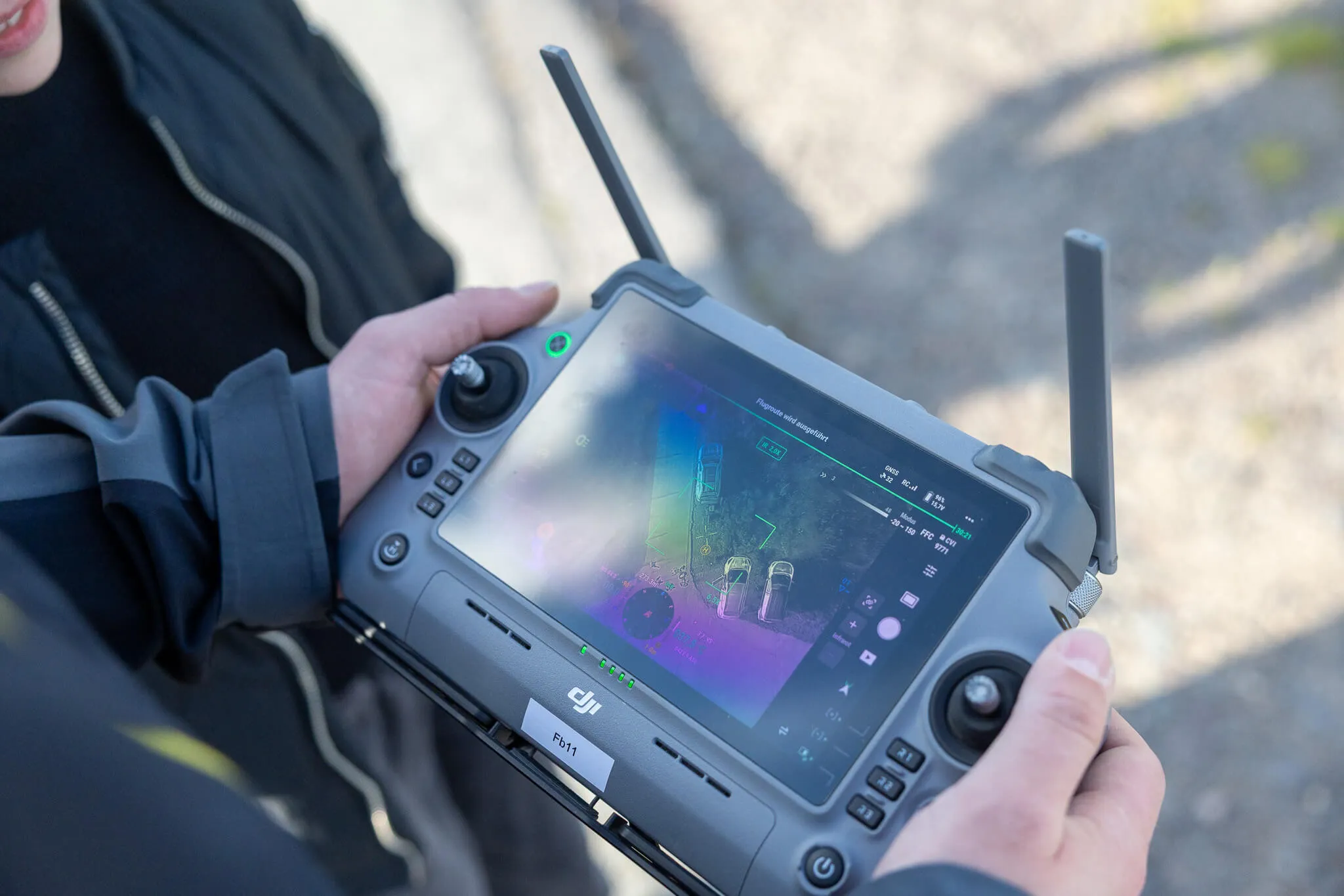 Person bedient ein DJI-Steuergerät mit angezeigter Kameransicht, vermutlich während einer Suchaktion.