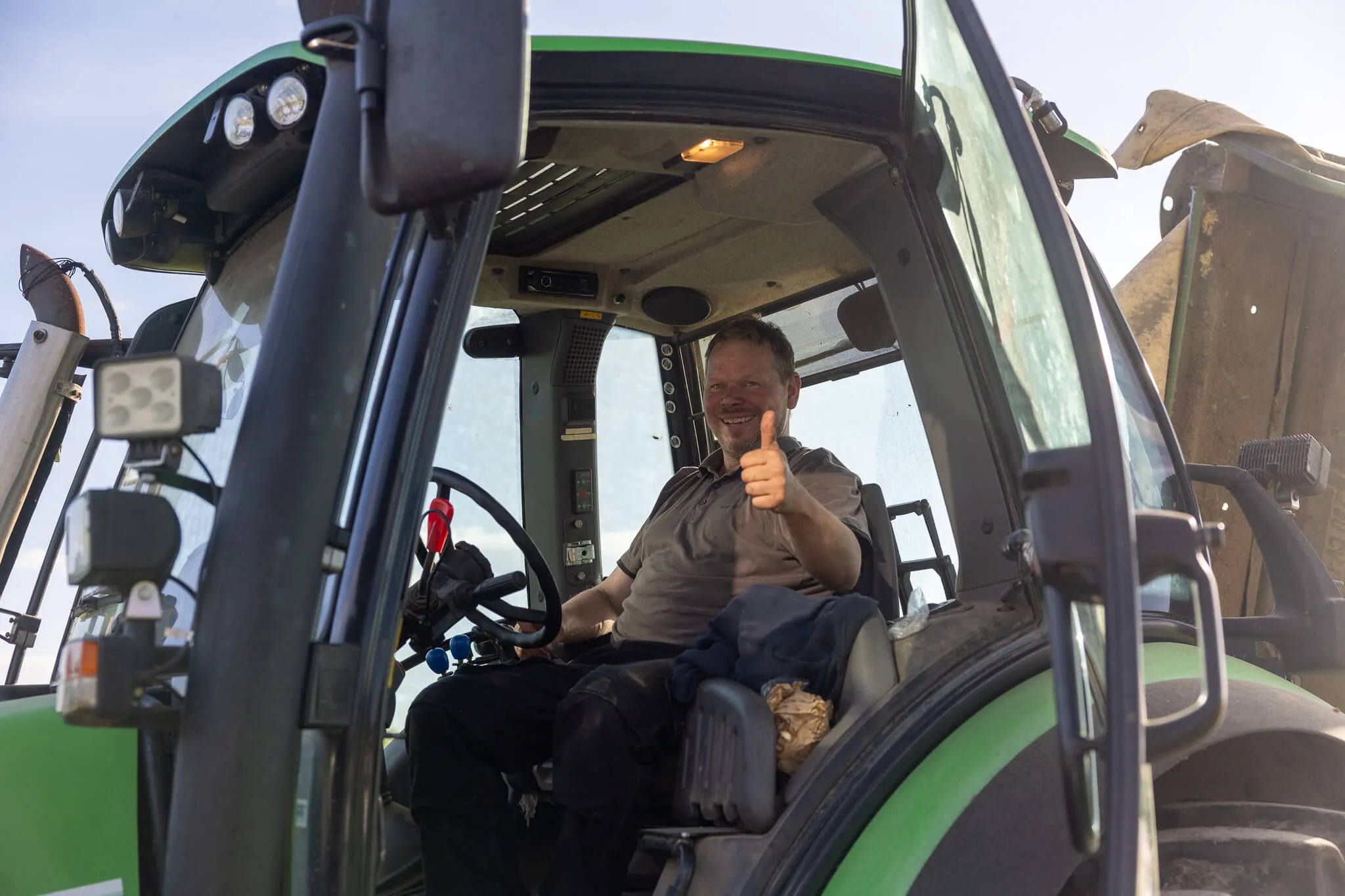 Landwirt Stefan Vogt sitzt lächelnd im Fahrersitz seines Traktors und zeigt den Daumen nach oben.