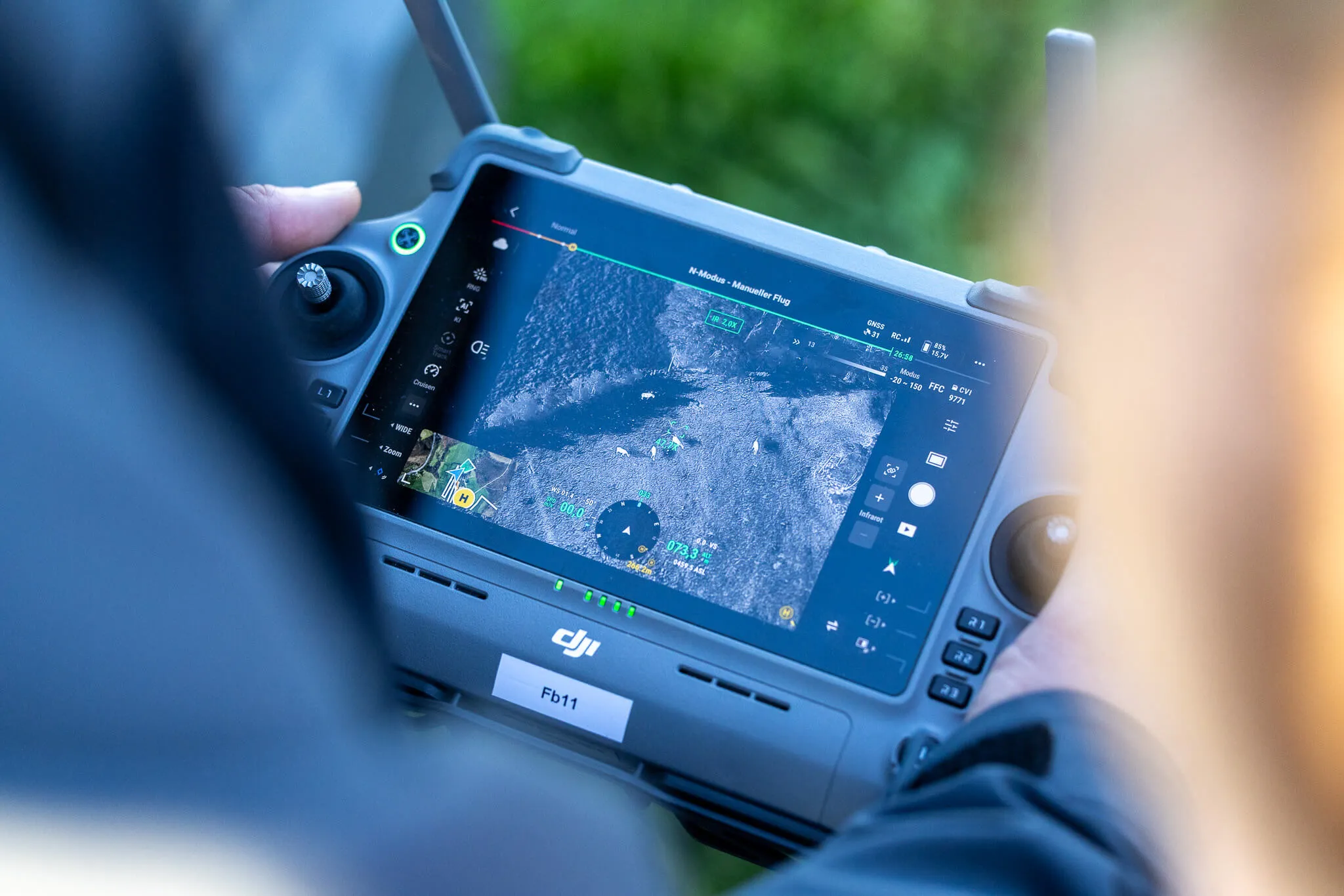 Nahaufnahme des Bildschirms einer DJI-Fernbedienung, der eine Karte mit einem markierten Suchgebiet und Flugdaten anzeigt. Die Aufnahme stammt von einer Drohnensteuerung während einer Suchaktion.