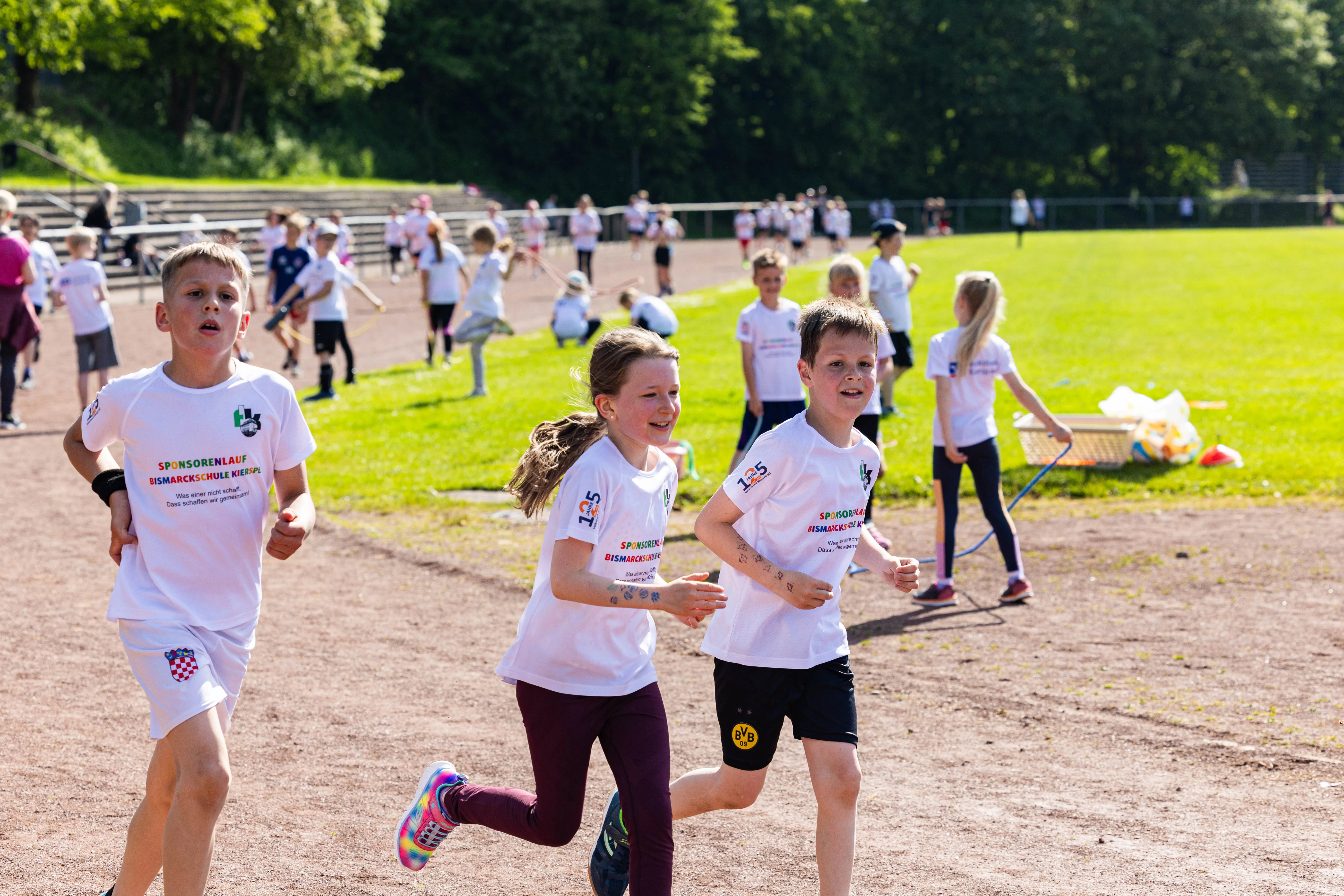 Schülerinnen und Schüler laufen bei einem Spendenlauf der Bismarckschule Kierspe, einige tragen Startnummern und T-Shirts mit dem Spendenlauf-Logo.