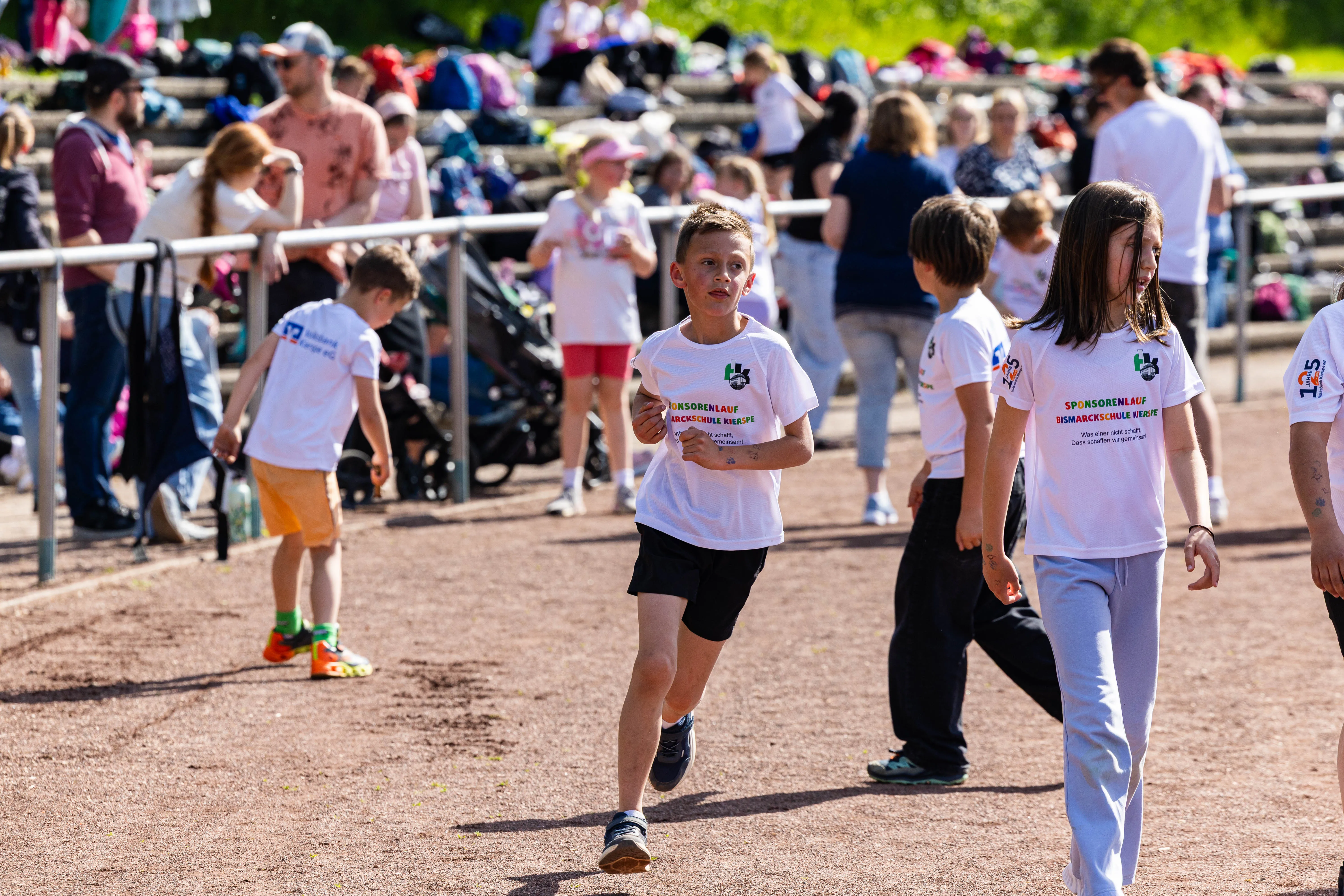 Schüler laufen bei einem Spendenlauf der Bismarckschule Kierspe auf einer roten Tartanbahn, einige tragen Startnummern auf ihren T-Shirts.