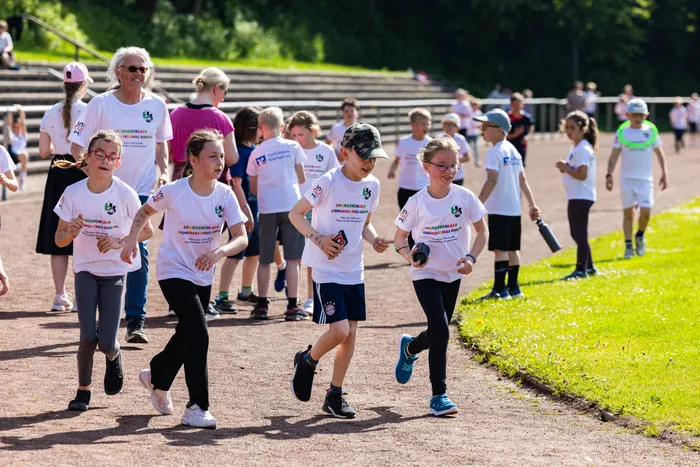 Schülerinnen und Schüler der Bismarckschule Kierspe laufen beim Spendenlauf für einen guten Zweck, einige tragen T-Shirts mit dem Aufdruck des Spendenlaufs.