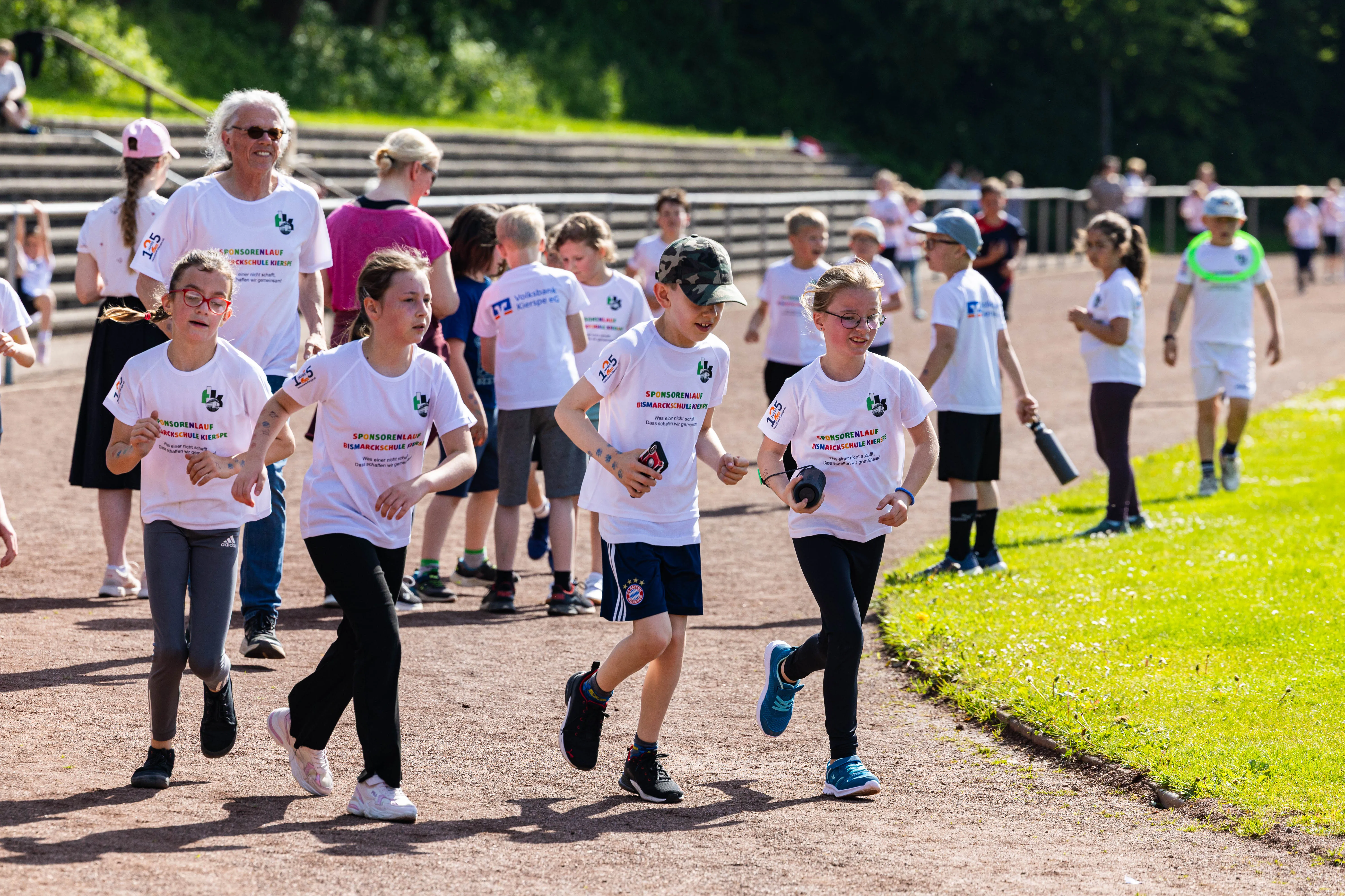 Schülerinnen und Schüler der Bismarckschule Kierspe laufen beim Spendenlauf für einen guten Zweck, einige tragen T-Shirts mit dem Aufdruck des Spendenlaufs.