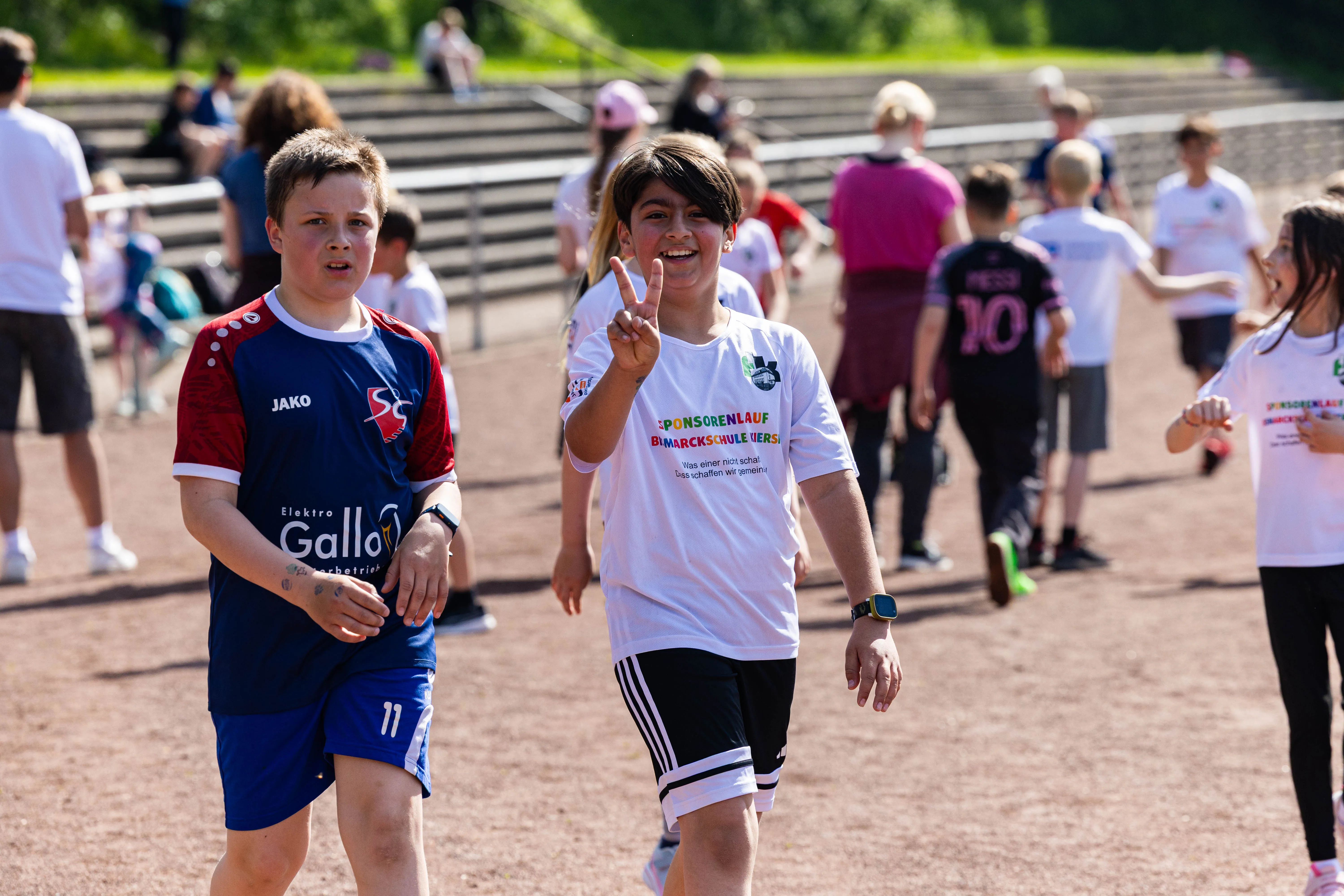 Zwei Schülerinnen und Schüler beim Spendenlauf der Bismarckschule Kierspe, die Schülerin zeigt die Zahl Zwei mit den Fingern.