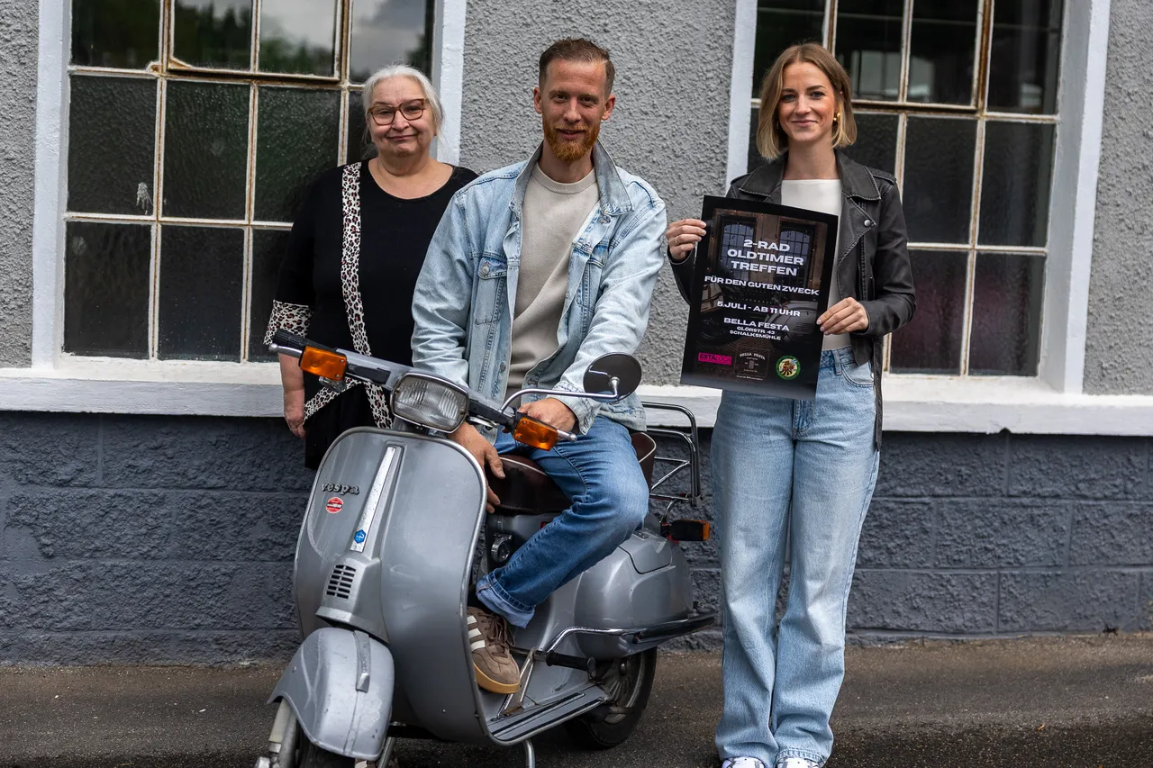 Drei Personen stehen vor einem grauen Roller. Links Astrid Lehmann von der Tafel Schalksmühle, in der Mitte Gion Patz und rechts Julia Patz von Bella Festa, die eine Ankündigung für ein Oldtimer-Treffen am 5. Juli halten.