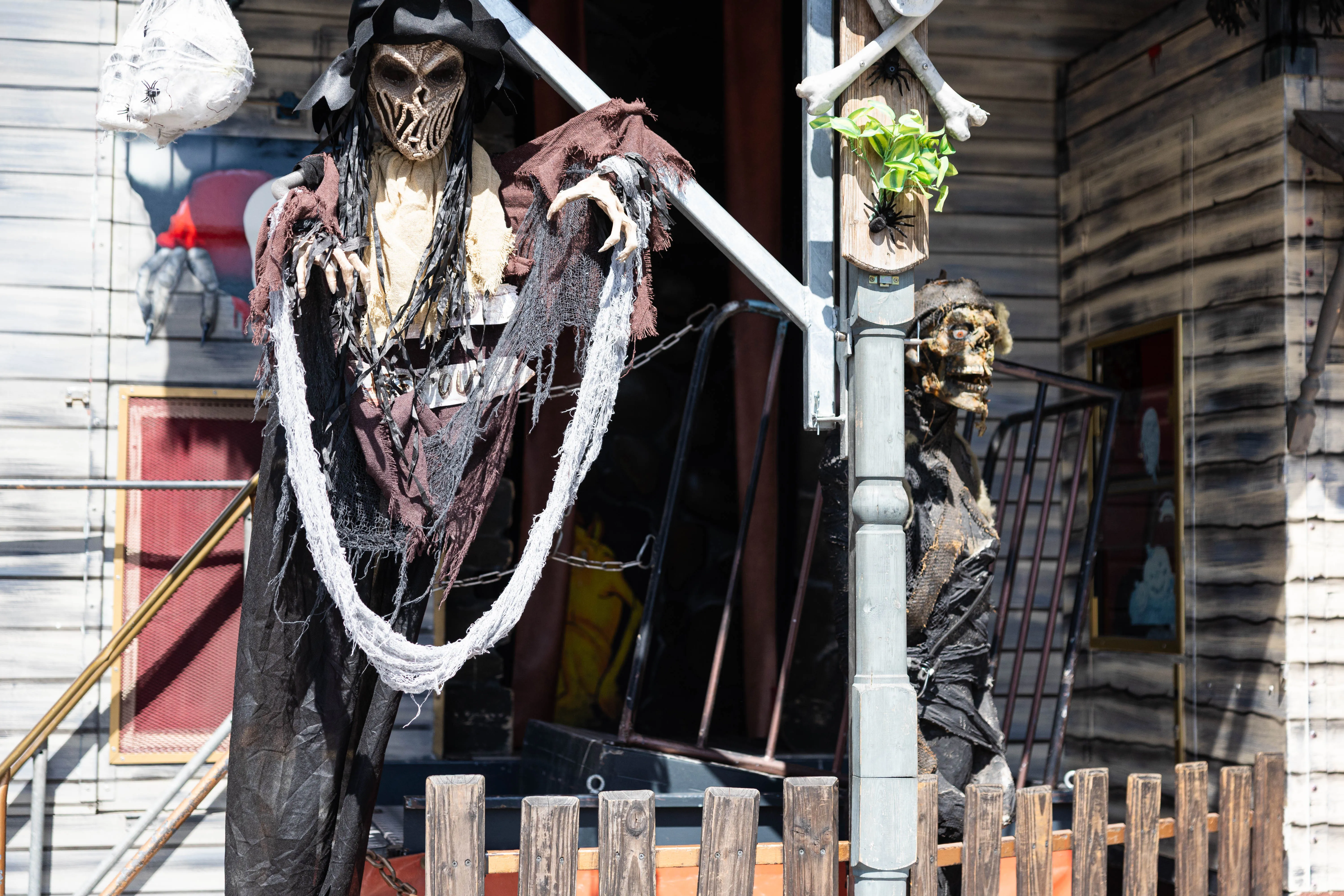 Zwei gruselig gestaltete Figuren im Piratenlook bewachen den Eingang zu einem Kirmesstand mit Holzfassade.