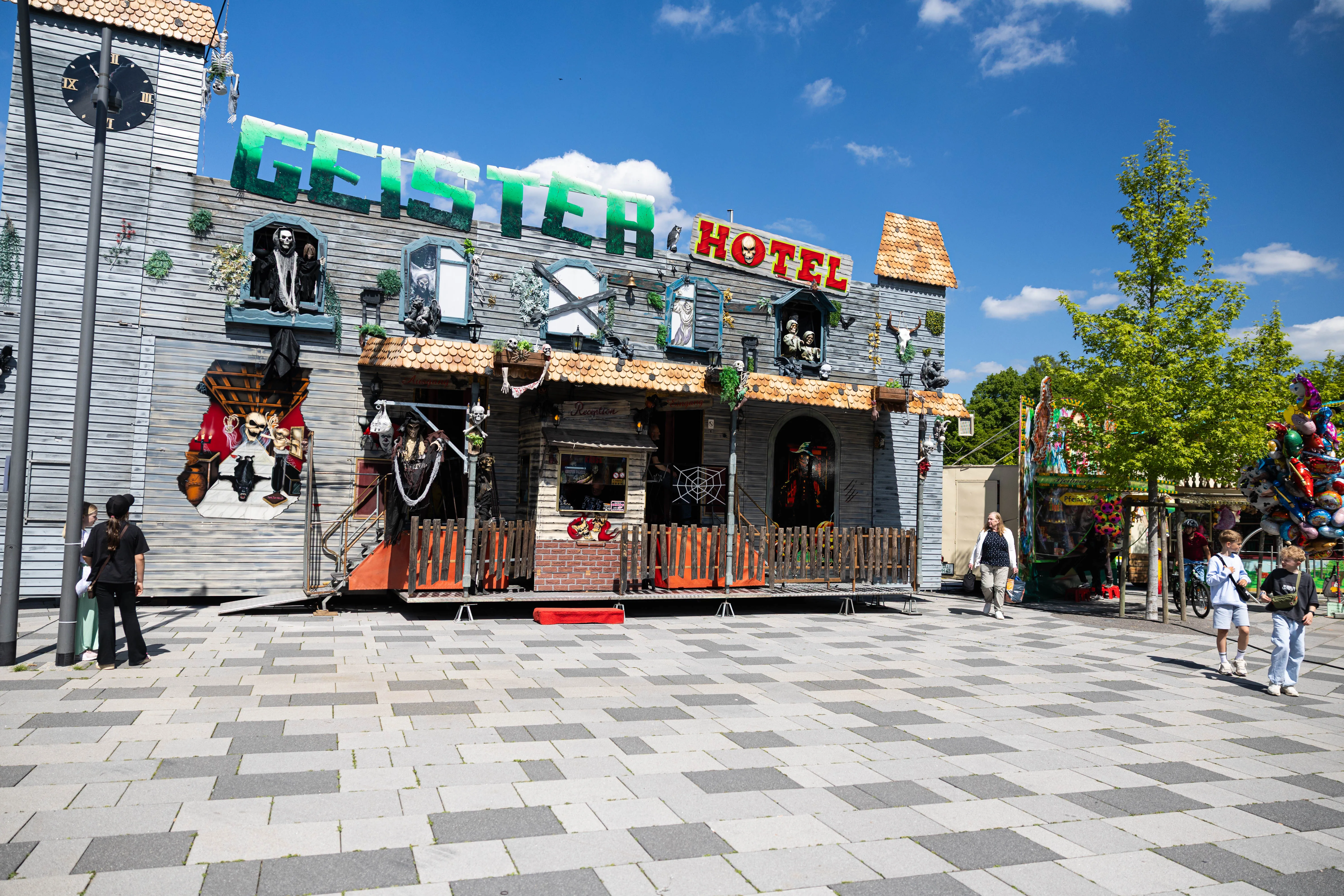 Das Geisterhotel auf der Meinerzhagener Pfingskirmes steht am hellen Tag auf einem gepflasterten Platz, wenige Besucher sind zu sehen.