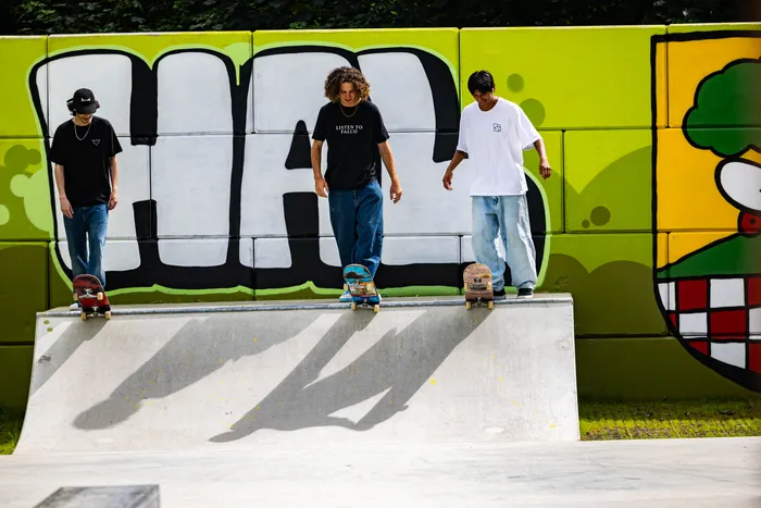 Drei junge Männer stehen auf Skateboard-Ramps in dem neu eröffneten Skatepark in Halver. Im Hintergrund eine bunt bemalte Wand.
