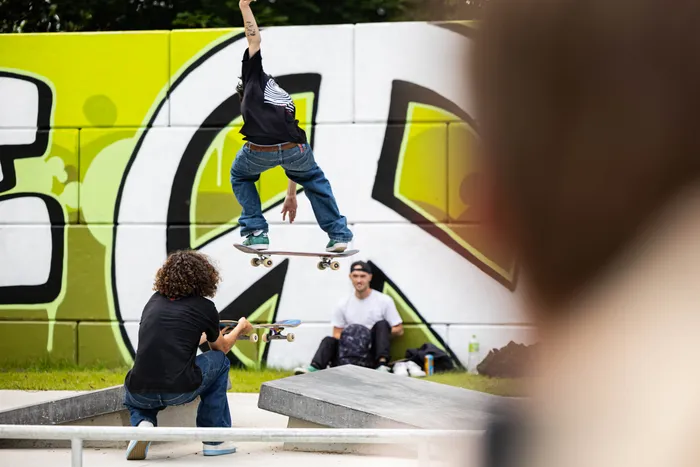 Ein Skater vollführt einen Trick in der Luft über einer Rampe im neu eröffneten Skatepark in Halver. Im Hintergrund sitzt ein weiterer Skater und beobachtet.