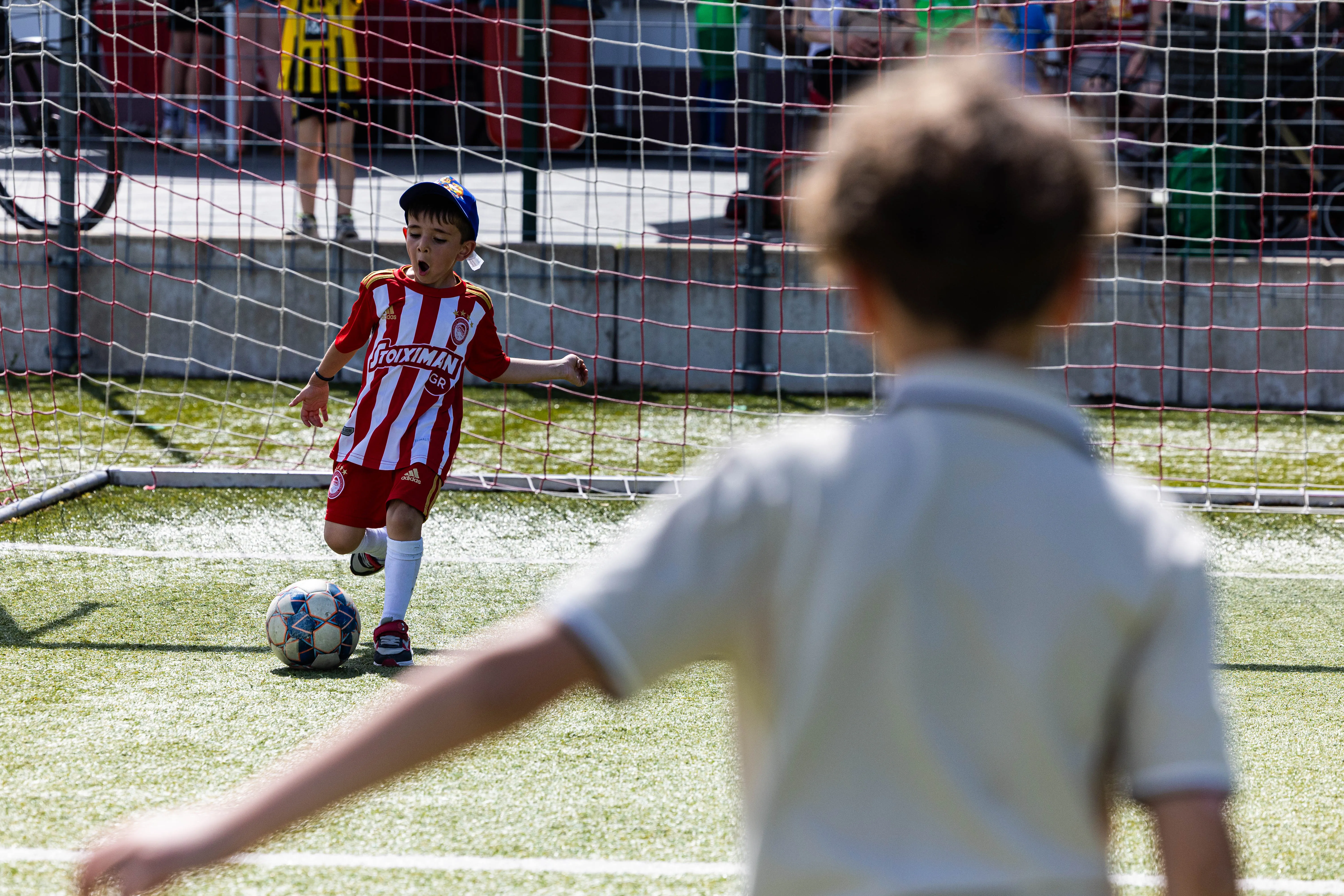 Junge im Fußballtrikot schießt auf das Tor, während ein zweiter Junge im Hintergrund steht.