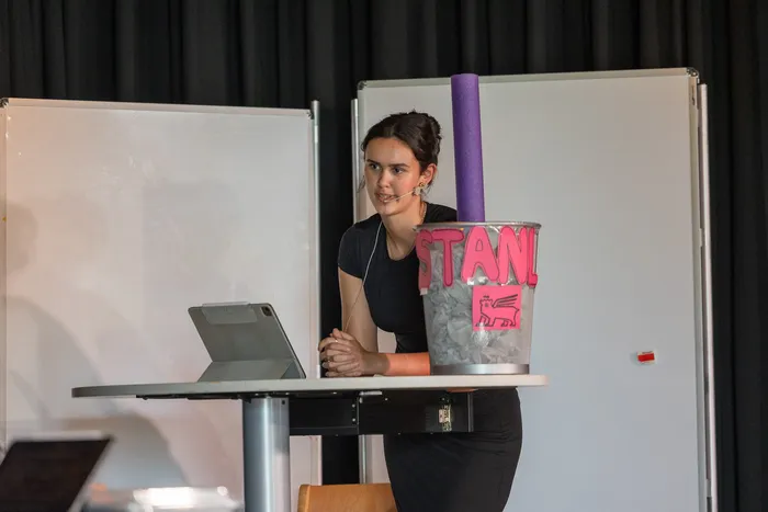 Eine junge Frau steht hinter einem Pult mit einem Tablet und einem Eimer mit der Aufschrift 