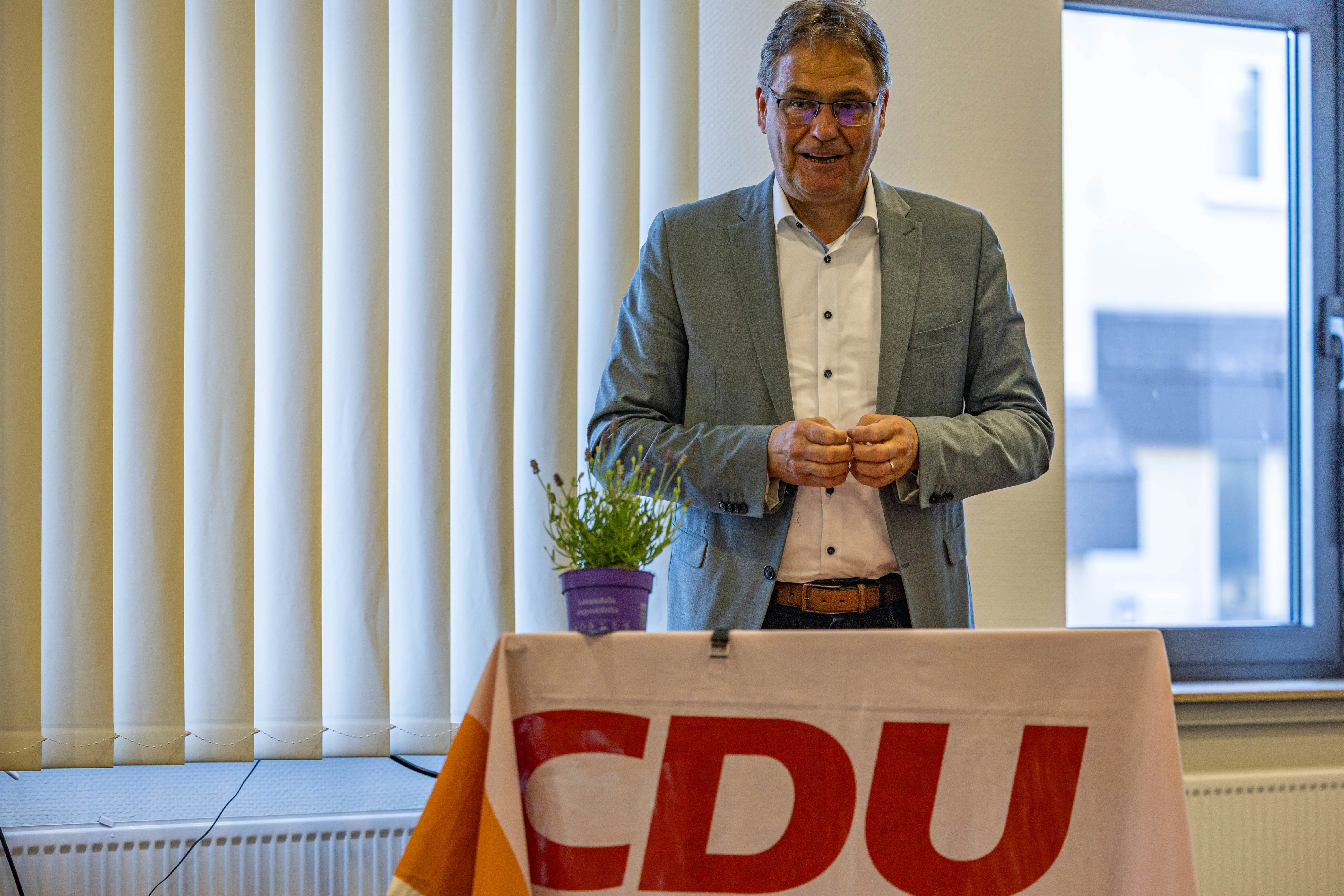 Dr. Peter Liese, Europaabgeordneter, hält Rede vor CDU-Logo und Pflanze. Im Hintergrund ein Fenster und vertikale Vorhänge.