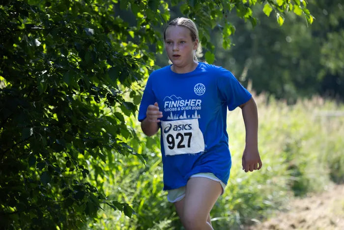 Eine junge Läuferin mit der Startnummer 927 trägt ein blaues T-Shirt mit der Aufschrift 