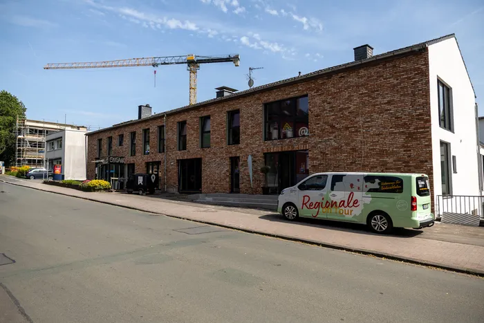 Zweistöckiges Backsteingebäude mit großen Fenstern, davor ein Lieferwagen mit der Aufschrift „Regionale on Tour“ und im Hintergrund ein Baugerüst mit Kran.